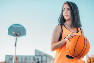 Jugadora y joven jugando al baloncesto con una pelota en una pista de juego para encestar el balon en la canasta © Migue Suarez
