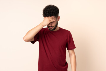 Young Moroccan man isolated on beige background with headache