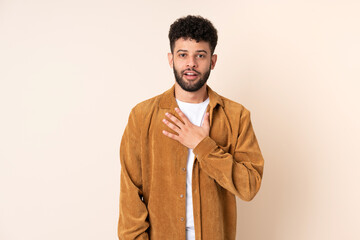 Young Moroccan man isolated on beige background surprised and shocked while looking right