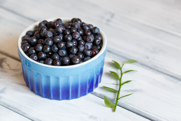 Blueberries in a blue cup on a white shabby table. Selective focus