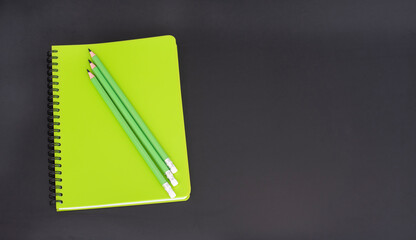 Top view of closed notebook with stationery on black school board.