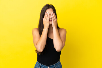 Young Brazilian woman isolated on yellow background covering eyes by hands