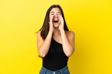Young Brazilian woman isolated on yellow background shouting and announcing something