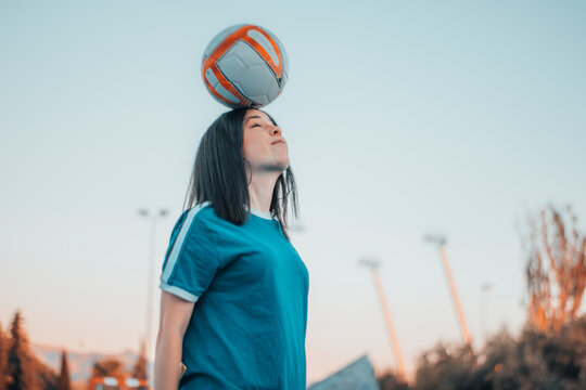 Chica jugando al futbol golpeando el balon en la pista de juego con la cabeza