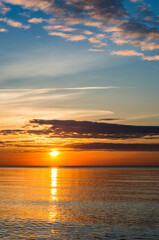 Sunset over the sea. Reflection of sunlight in the sea waves. Red and yellow sky in the rays of the sunset.