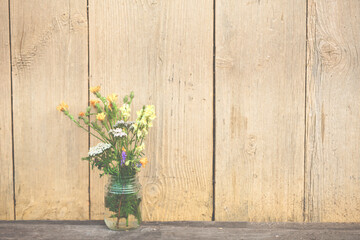 Bouquet of wildflowers on a rustic table and wooden wall at country cottage