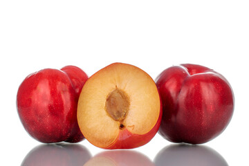 Fototapeta na wymiar Two whole and one half, in focus, ripe fragrant red plums, close-up, isolated on white.