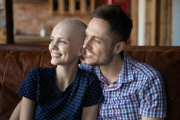 Happy young couple in love fighting with womans cancer, looking away at window, smiling at good...