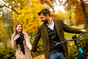 Young couple in the autumn park with electrical bicycle