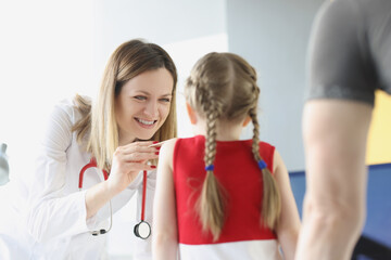 Doctor examines throat and mouth of little girl