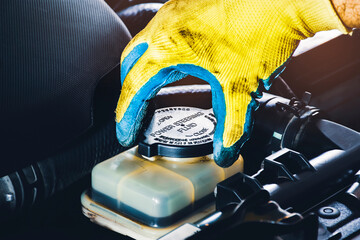 The mechanic hand is open or close the cap of the power steering fluid to check the hydraulic fluid...