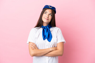 Airplane stewardess Brazilian woman isolated on pink background looking up while smiling