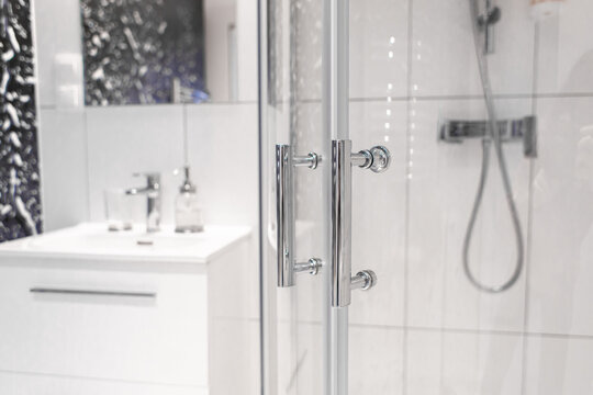 Close-up of chrome handles in a glass shower door. Modern bathroom interior