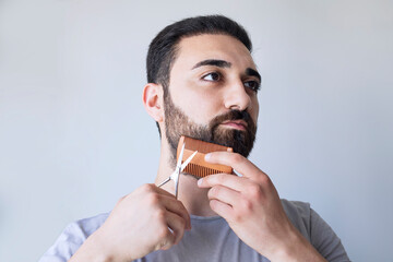 Portrait of a man cutting his beard with scissors. Selfcare during quarantine isolation