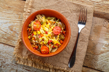 Risotto with mushrooms in a clay plate on a wooden background on a linen napkin next to a fork.