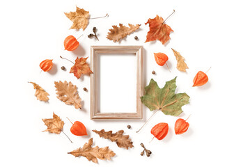 An empty wooden photo frame, physalis flowers, dried maple and oak leaves, cones and seeds are on a white background. Autumn, fall, thanksgiving day concept. Flat lay. Top view. Copy space.