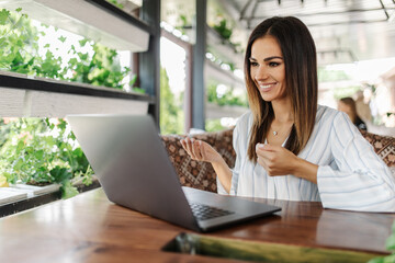 Young pretty woman making video call in cafe