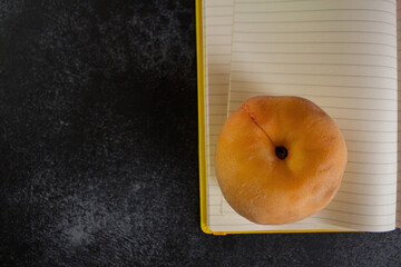 juicy peach on an open page of a yellow notebook