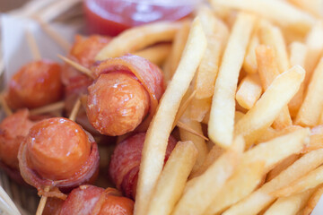 Close up sticky smorked bacon wrapped sausages and French Fry.
