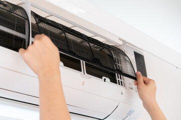 Asian woman changing a dirty and dusty air conditioner filter in bedroom. 