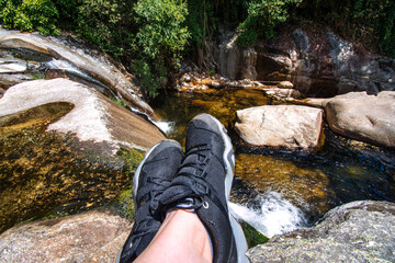 Feet Of An Unrecognizable Hiker Resting And Contemplating A Beautiful Landscape Of A River That Has...