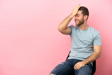 Young man sitting on a chair over isolated pink background has realized something and intending the solution