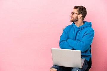 Young man sitting on a chair with laptop in lateral position