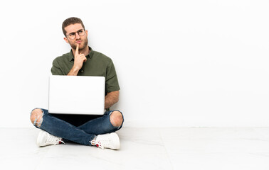 Young man sitting on the floor having doubts while looking up
