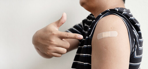 Asia man hand pointing to the shoulder with bandage has gone to vaccinate coronavirus covid19,...