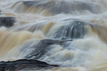 Fototapeta na wymiar Rough water in the river crashing against the rocks