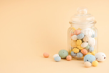 Multicolor Easter candy eggs on peach background.
