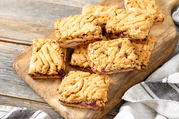 Shortbread cookies with cherry jam on a serving board on a light gray wooden kitchen table top view from a copyspace. Delicious homemade sweet pastries