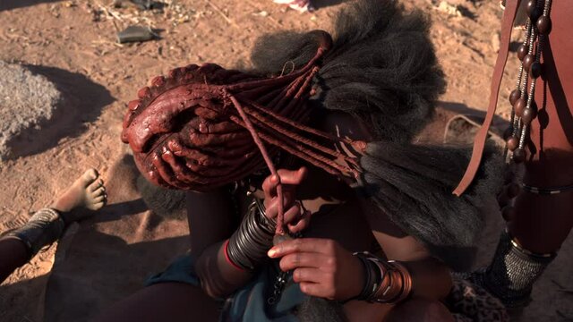 Himba woman doing her hair at traditional Himba village near Kamanjab in northern Namibia, Africa.