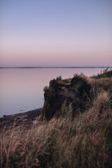 Pink sunset, sea horizon and cliff view