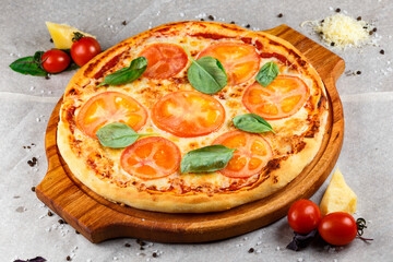 pizza margarita on a wooden board on a parchment background with ingredients