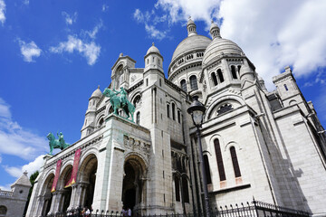 Basilica of the Sacred Heart of Paris under a blue cloudy sky and sunlight in Paris, France