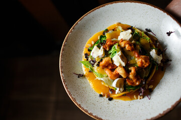 salad with shrimps and brie cheese in a white plate on a dark background
