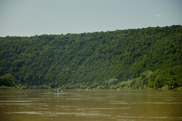  Beautiful river summer landscape. In the distance, people are sailing in a kayak.