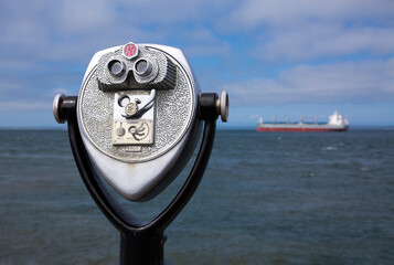 Retro coin-operated binoculars - also known as tourist binoculars - point to a large ship off the coast of Westport, WA
 - obrazy, fototapety, plakaty
