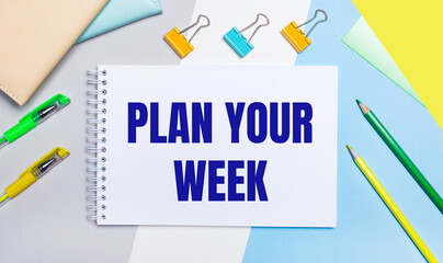 On a gray and blue background are stationery of yellow-green color, a notebook with the text PLAN YOUR WEEK. Flat lay.