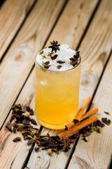 bright bourbon-based cocktail with cinnamon and cloves on a wooden background with lines. bar menu concept