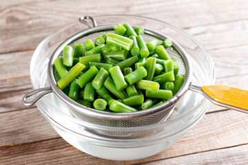 Colander with raw green bean on a table