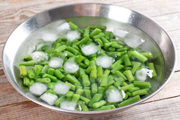 Boiled vegetables, green beans in ice water after blanching on a table