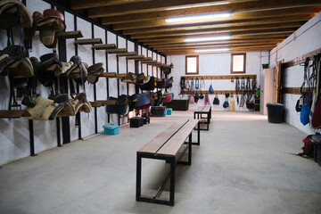 Storage room with horse saddles and bridles.