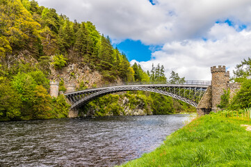 Fototapeta premium A view up the River Spey towards the castellated tower bridge at Craigellachie, Scotland on a summers day