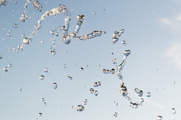 Water shed splashes from watering in summer garden with sprinkler on grass lawn and sky background....