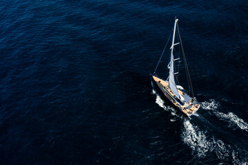 View from above, stunning aerial view of a sailboat sailing on a blue water at sunset.Sardinia,...