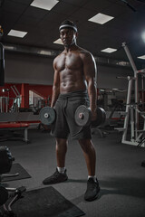 Fototapeta na wymiar Muscular african american man exercising with weights. Power athletic guy on training pumping up muscles with dumbbells