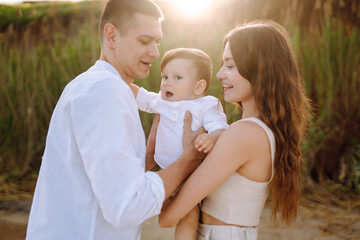 Happy young family with little baby boy spending time together on the beach. Family, childhood, ecology and people.