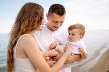 Happy young family with little baby boy spending time together on the beach. Family, childhood, ecology and people.